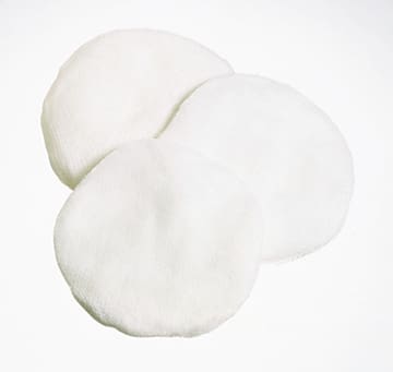 Three white round pillows on a white surface.