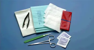 A surgical kit with scissors, bandages and towels.