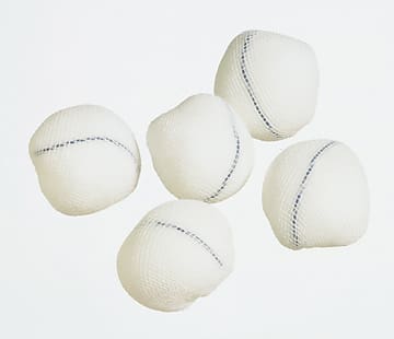 Five white tennis balls on a white surface.