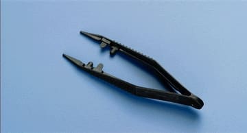 A pair of black pliers on a blue surface.