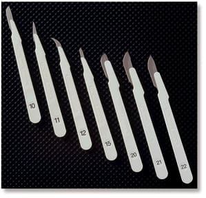 A set of six white plastic tweezers on a black surface.