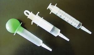 Three plastic syringes with a green syringe.