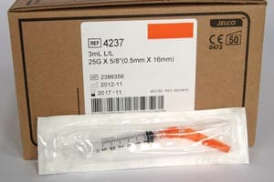 An orange syringe is sitting on top of a box.