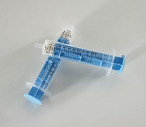 Two blue syringes on a white surface.