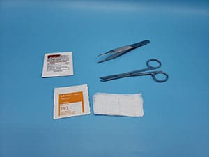 A pair of scissors, a bandage, and other items on a blue surface.