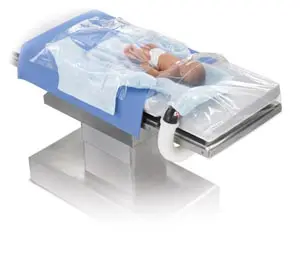 A baby is laying on a table with a plastic cover.