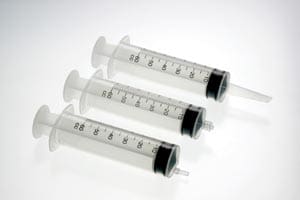 Three plastic syringes on a white background.