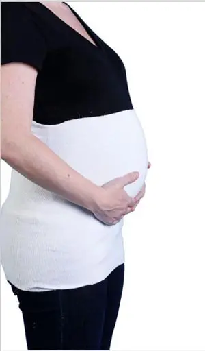 A pregnant woman wearing a white belly band.