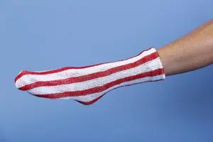 A person's hand holding a red and white striped sock.