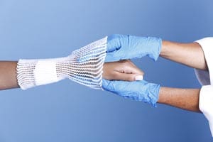 A man in blue gloves is holding a woman's hand.