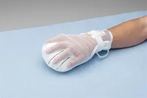 A person wearing a glove on a bed.