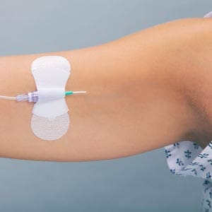 A woman with a syringe attached to her arm.