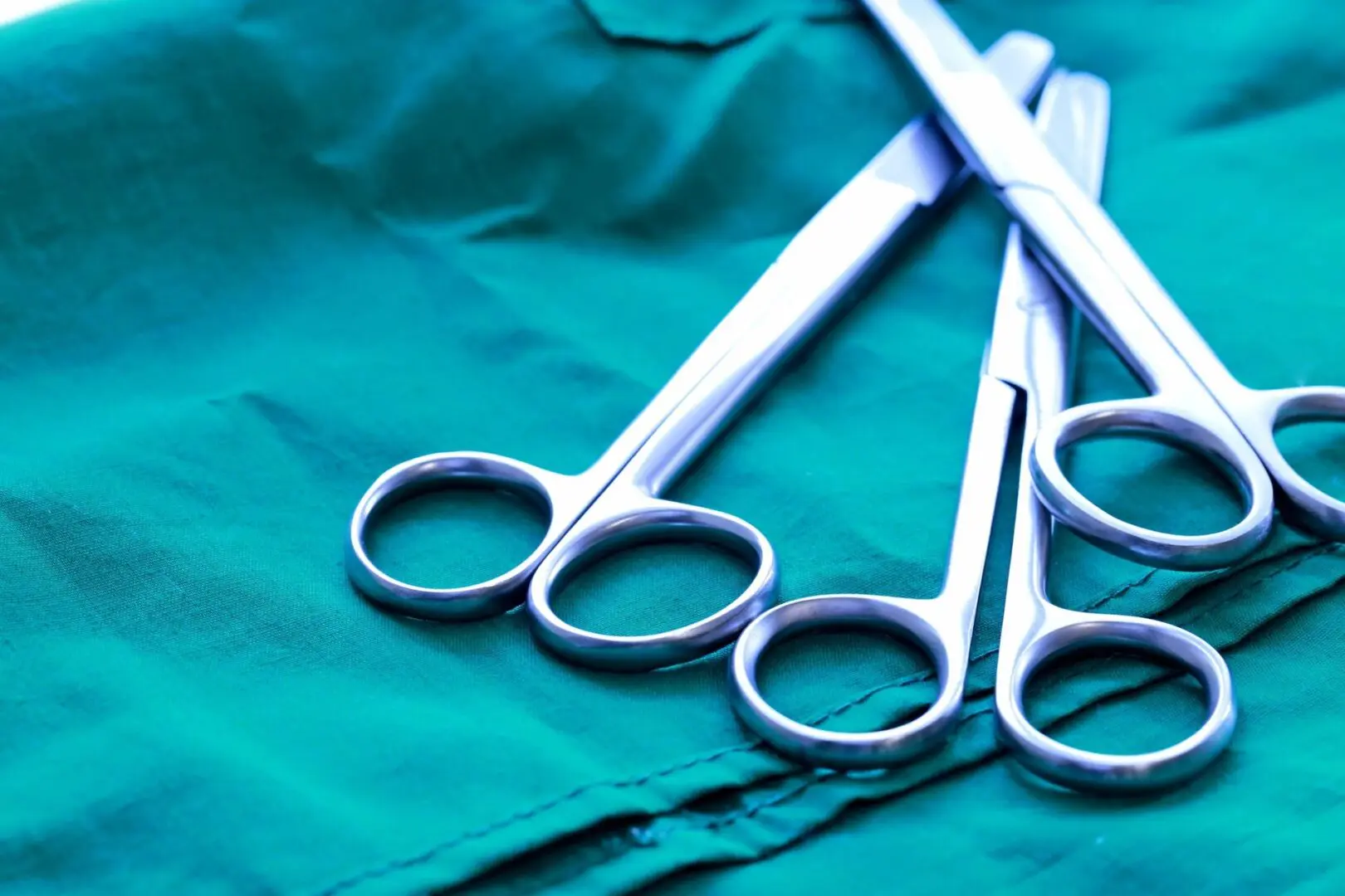 A pair of scissors on a green cloth.