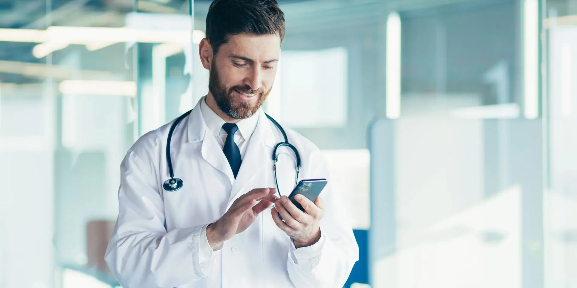 A man in a lab coat is looking at his phone.