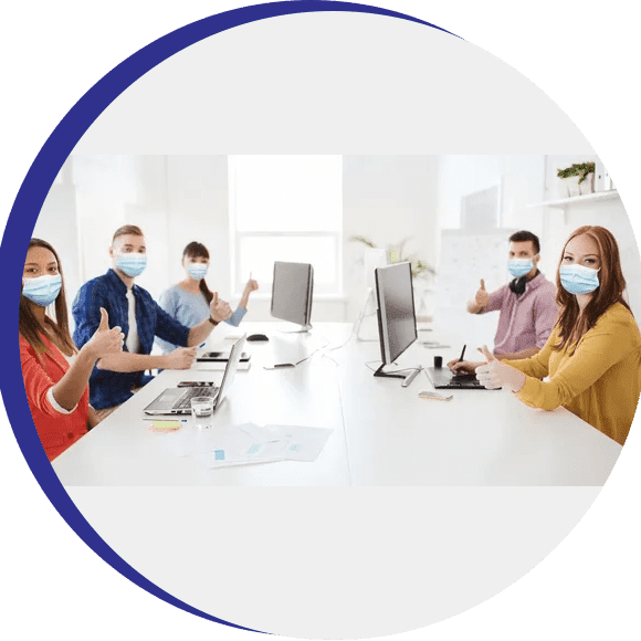 A group of people sitting around a table wearing masks.